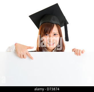 Portrait of smiling Asian female student en robe de deuxième cycle montrant l'espace vierge sur la bannière, isolé sur fond blanc Banque D'Images