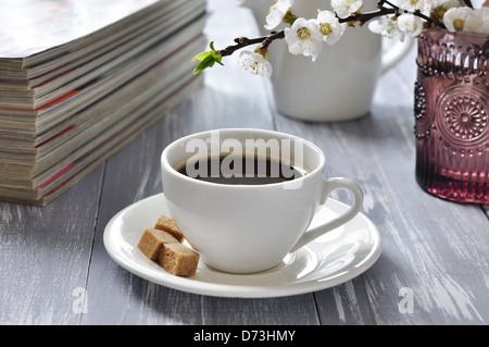 Tasse de café avec des branches de cerisier en fleurs sur fond de bois Banque D'Images