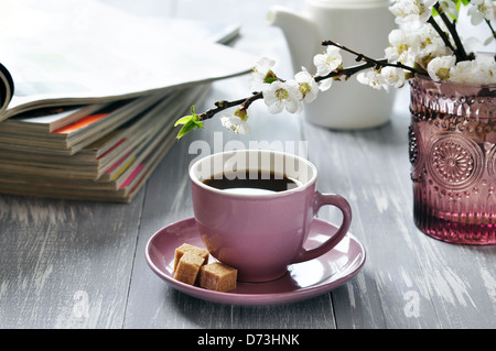 Tasse de café avec des branches de cerisier en fleurs sur fond de bois Banque D'Images