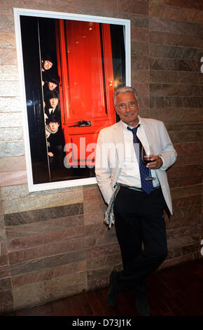 Photographe français Jean-Marie Perier soulève un verre qu'il pose en face d'une photographie intitulée 'les Beatles' à partir de 1964, lors du vernissage de l'exposition photo de "rampe" à Munich, Allemagne, 24 avril 2013. Photo : Felix Hoerhager Banque D'Images