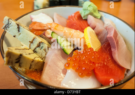 Bol de Chirashi Sushi avec sélection de tamago, le saumon, le thon, les oeufs de poisson, Saba, wasabi, le poulpe sur un lit de riz à sushi. Banque D'Images