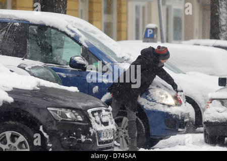 Berlin, Allemagne, une femme libéré sa voiture de la neige Banque D'Images