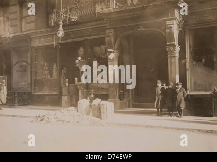 Cette image historique capture des immeubles de location à New York où le travail à domicile était une pratique courante, mettant en évidence les conditions de vie de l'époque. La photo offre un aperçu de la vie quotidienne des résidents engagés dans diverses formes de travail dans leurs maisons. Banque D'Images