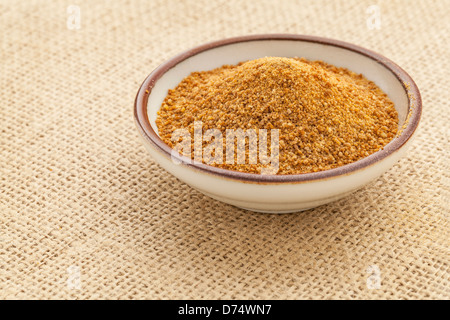 Petit bol en céramique de sucre non raffiné de cocotier contre une toile de jute Banque D'Images