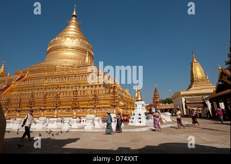 Les habitants de la Birmanie à pied passé le grand dôme d'or de la Pagode Shwezigon Bagan Myanmar (Birmanie) Banque D'Images