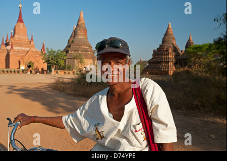 L'homme et son birman location debout devant des temples en pierre au coucher du soleil à Bagan Myanmar (Birmanie) Banque D'Images