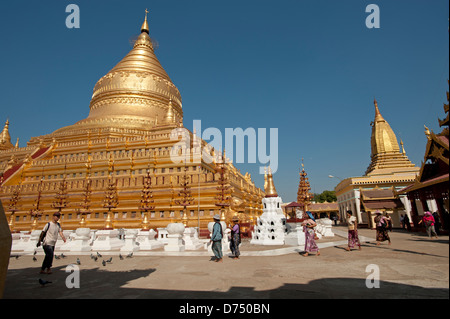 Les habitants de la Birmanie à pied passé le grand dôme d'or de la Pagode Shwezigon Bagan Myanmar (Birmanie) Banque D'Images