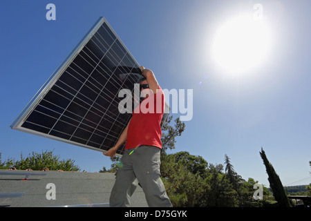 Torre Alfina, l'Italie, l'homme porte un collecteur solaire sur le toit d'une maison individuelle Banque D'Images