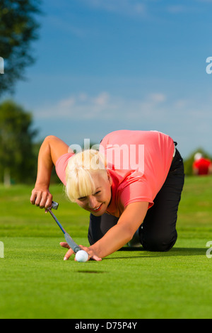 Jeune joueur de golf féminin sur son cours visant à mettre Banque D'Images