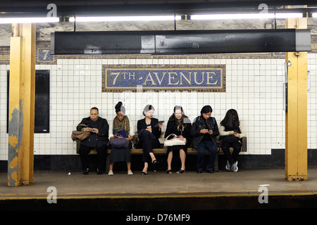 Les passagers d'attendre un train sur le quai de la station de métro de la 7e Avenue à Brooklyn, New York. Banque D'Images