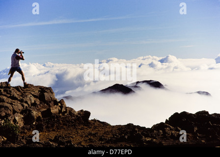 Escalade en montagne photographe tire le lever du soleil au-dessus de l'image nuages Volcan Haleakala Maui Hawaii Banque D'Images