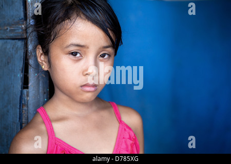 Jeune fille Philippine 8 ans avec l'expression triste et sombre sur le bleu, la pauvreté dans les Philippines. Banque D'Images