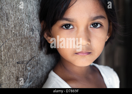 Portrait d'une jolie petite fille de 8 ans dans la pauvreté Philippines frappées par quartier, d'un éclairage naturel. Banque D'Images