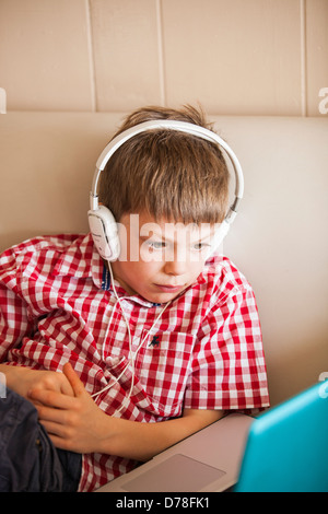 Boy using laptop et écouteurs Banque D'Images