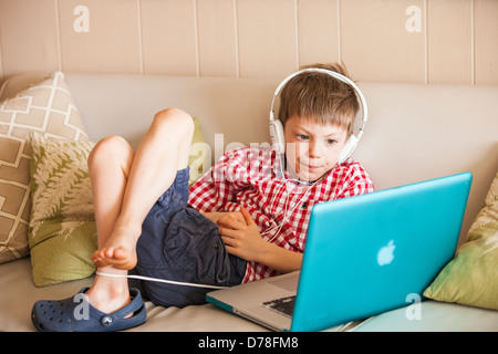 Boy using laptop et écouteurs Banque D'Images