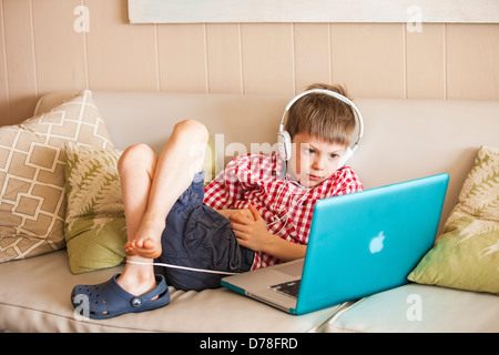 Boy using laptop et écouteurs Banque D'Images