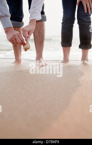 Jeune couple à la recherche de coquillages sur la plage, Close up sur les jambes et les mains Banque D'Images