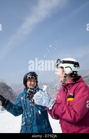 Jeune homme et femme jouant dans la neige en station de ski Banque D'Images