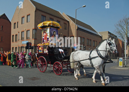 Une calèche mène une procession d'hommes et de femmes indiennes, en costume traditionnel, à travers les rues de Bedford Banque D'Images