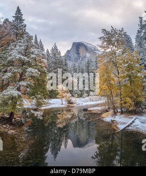 Yosemite National Park, Californie : Demi Dôme réfléchissant sur la rivière Merced avec de la neige fraîche le long des rives Banque D'Images
