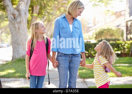 La mère et les filles à l'école à pied sur la rue de banlieue Banque D'Images