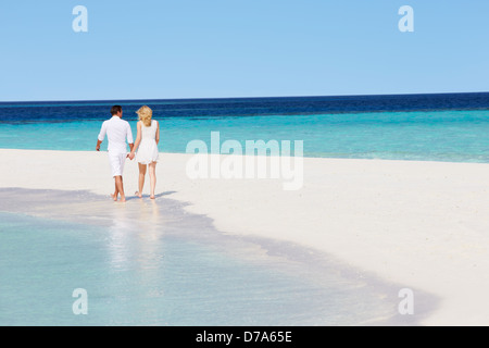 Vue arrière du Couple Walking on Tropical Beach Banque D'Images