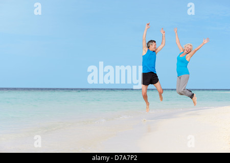 Senior Couple sautant sur Belle Plage Banque D'Images