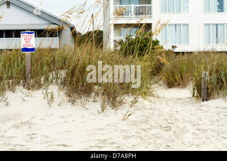 Un ' ne pas marcher sur des Dunes de signer sur la gauche en face de la plage avec des maisons dans l'arrière-plan. 2 personnes par guide post en bois en toute sécurité Banque D'Images