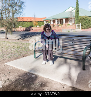 Femme assise sur le banc de parc avec nouveau chiot Banque D'Images