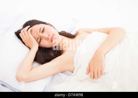 Femme malade au lit de toucher sa tête Banque D'Images