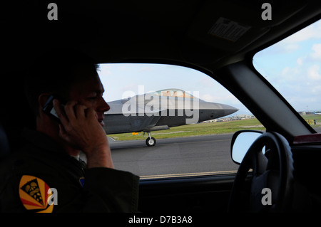 L'US Air Force F-22 Raptor avion de chasse furtif décolle comme un membre de l'équipe de sécurité montres de sa voiture le long de la piste le 6 avril, 2013 at Joint Base Harbor-Hickam Pearl, Washington. Banque D'Images