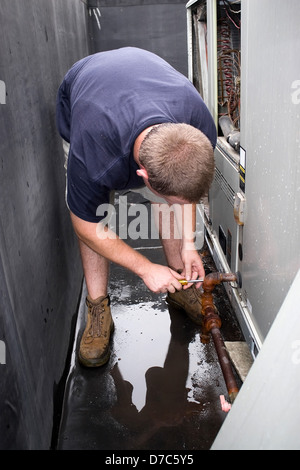Une ventilation chauffage ventilation climatisation technicien travaillant sur une grande unité commerciale. Banque D'Images
