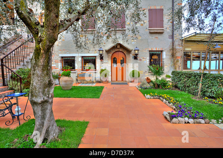 Belle terrasse avec arbres et fleurs à l'entrée de restaurant situé dans maison typiquement italien de Sirmione, Italie. Banque D'Images