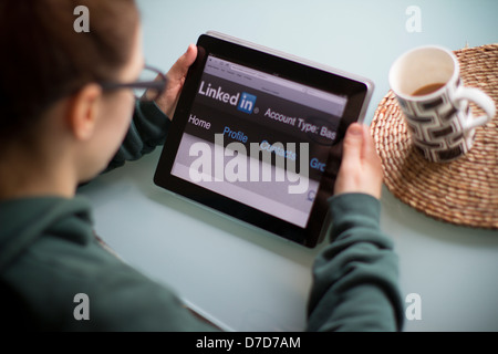 Jeune femme à la recherche liée à l'ipad avec écran sur Linkedin Banque D'Images