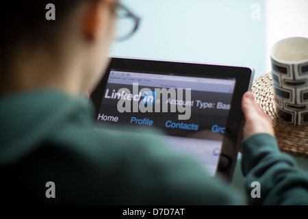 Jeune femme à la recherche liée à l'ipad avec écran sur Linkedin Banque D'Images