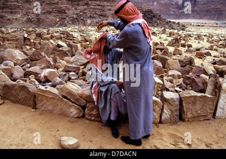 Bédouins portant un keffieh à carreaux blancs et rouges et des robes traditionnelles dans le désert de Wadi Rum connu aussi sous le nom de la vallée de la lune, dans le sud de la Jordanie Banque D'Images