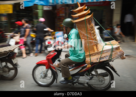 Un homme sur sa moto transportant un grand morceau de meubles en bois à travers les rues de la vieille ville, Hanoi Banque D'Images