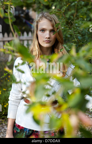 Belle teen derrière tree in garden Banque D'Images