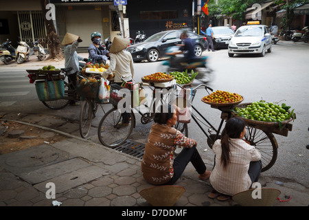 Les vendeurs de rue qui vendent leurs fruits sur leurs vélos dans le vieux quartier de Hanoi, Vietnam Banque D'Images