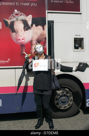 Bristol, Royaume-Uni,Mai 4th,2013. Manifestant une femme portant un masque blanc et portant une caisse enregistreuse pose à côté d'une publicité sur un bus passant montrant une photo d'un cochon qu'elle participe à des manifestations contre le projet de privatisation de la NHS. Credit : lynchpics / Alamy Live News Banque D'Images