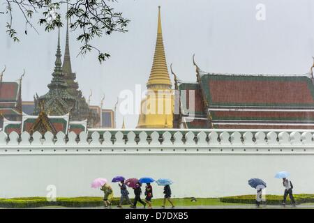 Bangkok, Thaïlande. 5 mai, 2013. Les touristes avec umbellas à pied à travers un orage passé les parois du Grand Palais avant l'Bhumibol Adulyadej, le Roi de Thaïlande, arrivé pour un événement de jour du couronnement. Le 5 mai marque le 63e anniversaire du couronnement de Sa Majesté le Roi Bhumibol Adulyadej. La journée est célébrée comme une fête nationale ; depuis cette année, il tombe un dimanche, le jour férié sera célébrée le lundi 6 mai, et à ce titre tous les bureaux gouvernementaux et les banques commerciales se ferme pour la journée. Sa Majesté le Roi Bhumibol Adulyadej est le plus ancien monarque régnant dans le monde. Chaque année le Banque D'Images