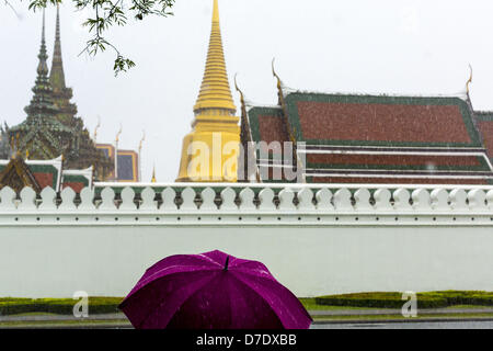 Bangkok, Thaïlande. 5 mai, 2013. Les touristes avec umbellas à pied à travers un orage passé les parois du Grand Palais avant l'Bhumibol Adulyadej, le Roi de Thaïlande, arrivé pour un événement de jour du couronnement. Le 5 mai marque le 63e anniversaire du couronnement de Sa Majesté le Roi Bhumibol Adulyadej. La journée est célébrée comme une fête nationale ; depuis cette année, il tombe un dimanche, le jour férié sera célébrée le lundi 6 mai, et à ce titre tous les bureaux gouvernementaux et les banques commerciales se ferme pour la journée. Sa Majesté le Roi Bhumibol Adulyadej est le plus ancien monarque régnant dans le monde. Chaque année le Banque D'Images