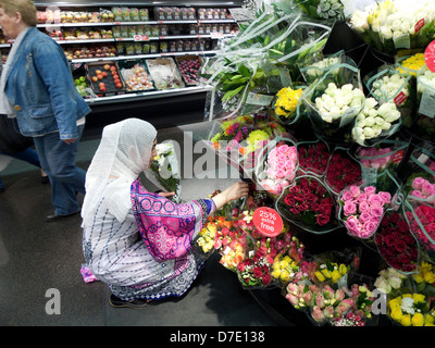 Une femme musulmane en robe colorée achetant de belles fleurs coupées Au magasin M&S Inside Marks & Spirers de Cardiff Centre du pays de Galles Royaume-Uni KATHY DEWITT Banque D'Images