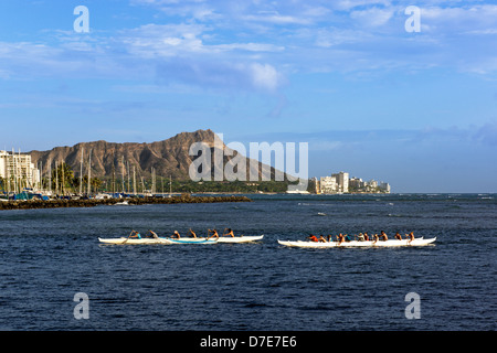 Deux équipes de course de canoë sprint vers le rivage à Ala Moana Beach, Diamond head derrière, sur l'île d'Oahu, Hawaii. Banque D'Images