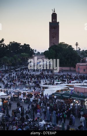 Maroc, Marrakech - Place Jemaa el Fna. Vue sur la place en soirée, avec la mosquée Koutoubia. Banque D'Images