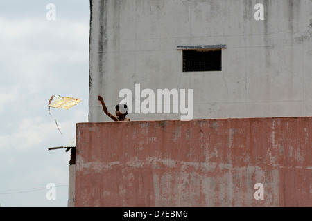 Un garçon lance son cerf-volant d'un toit à Tiruvannamalai, Tamil Nadu, Inde Banque D'Images