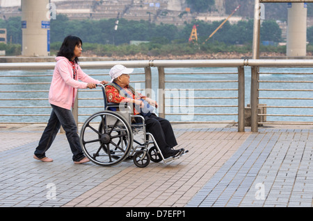 Mobilité Asian personne étant dans un fauteuil roulant poussé par un membre de la famille - probablement grand-mère et sa petite-fille Banque D'Images