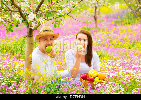 Jeune beau couple having picnic en plein air en été, mordre apple vert frais, détente à l'extérieur, concept d'amour Banque D'Images