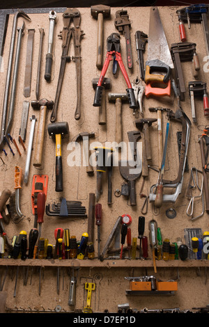 Une collection d'outils domestiques stockés sur le mur d'un petit garage ferme. Banque D'Images