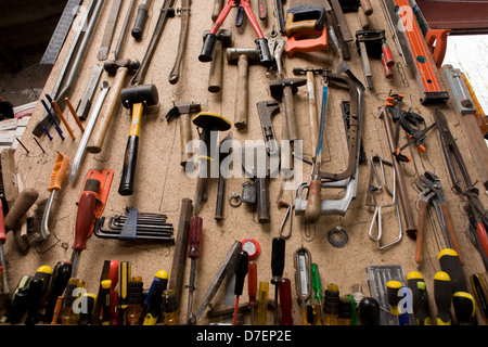 Une collection d'outils domestiques stockés sur le mur d'un petit garage ferme. Banque D'Images